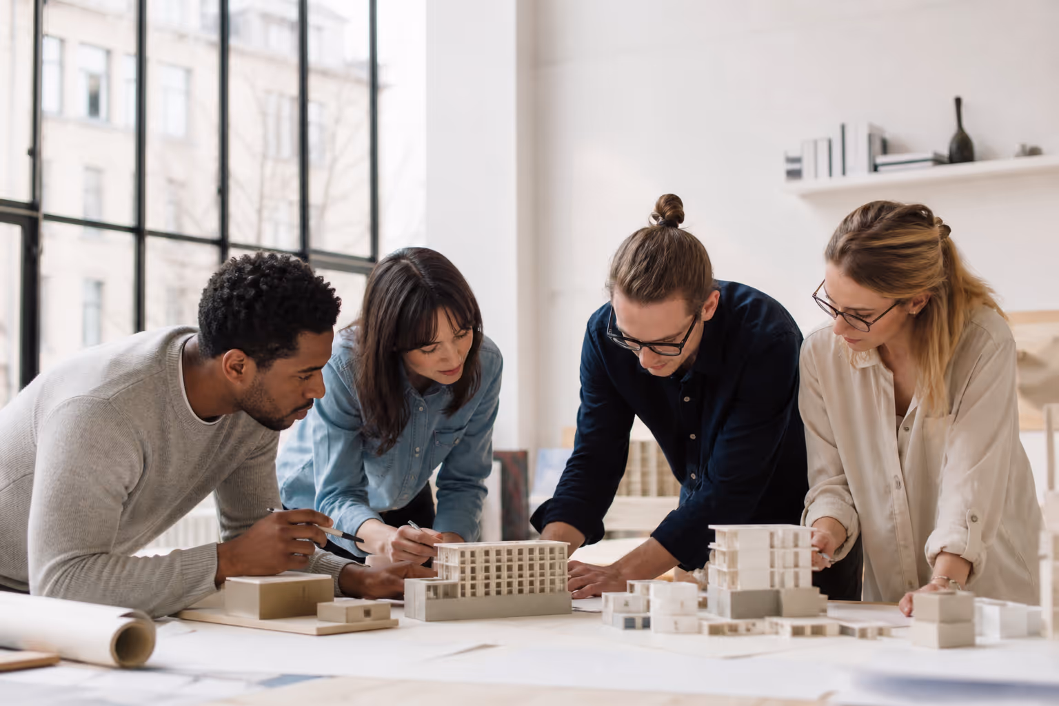 Architects at Lineá collaborating over physical models in a bright, minimalist studio